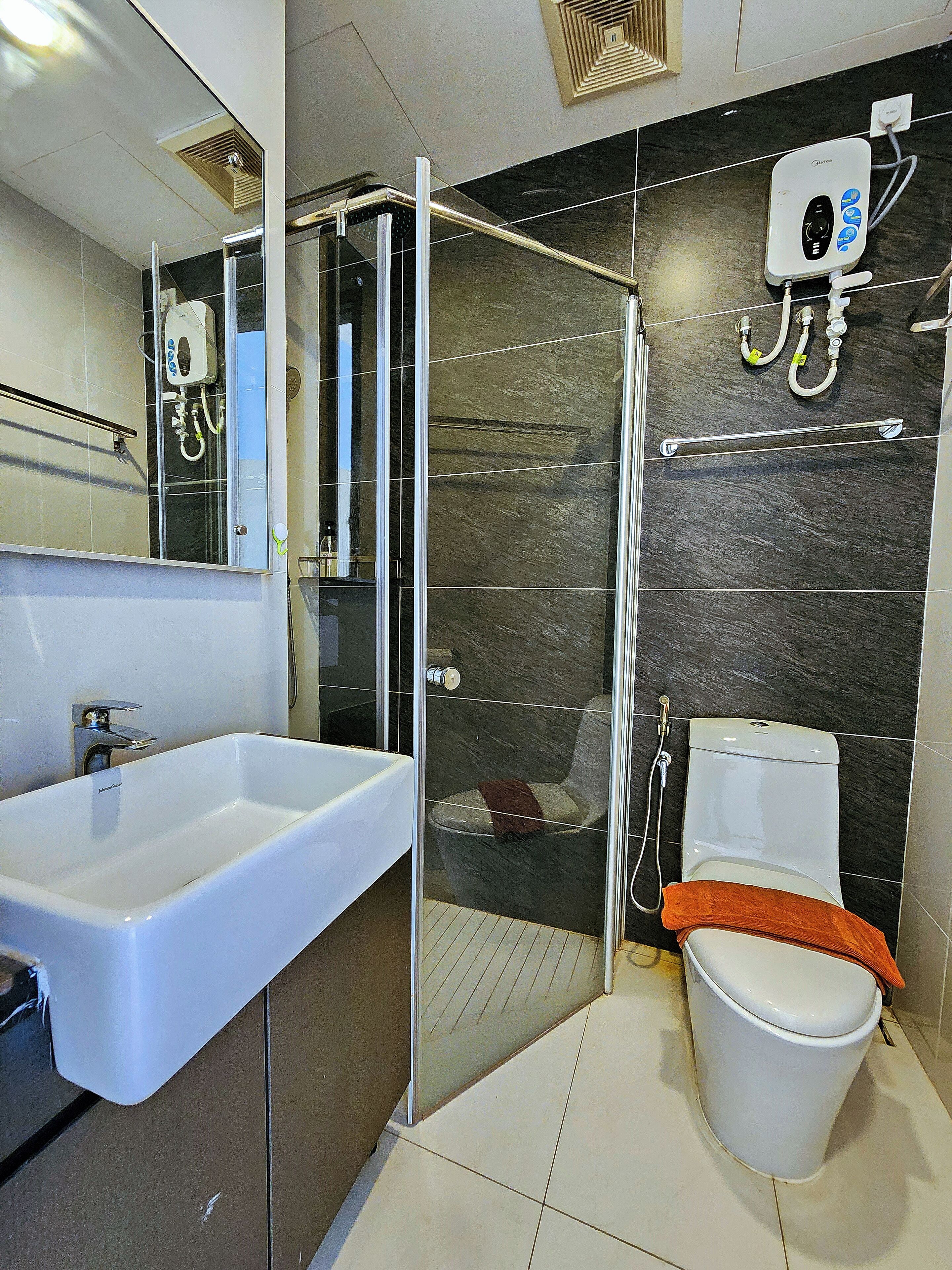 Une salle de bain moderne avec une douche à parois de verre, un lavabo blanc et des toilettes.