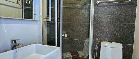 Une salle de bain moderne avec une douche à parois de verre, un lavabo blanc et des toilettes.