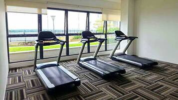 A room with three treadmills, large windows with a view of a green landscape, and a patterned carpet.