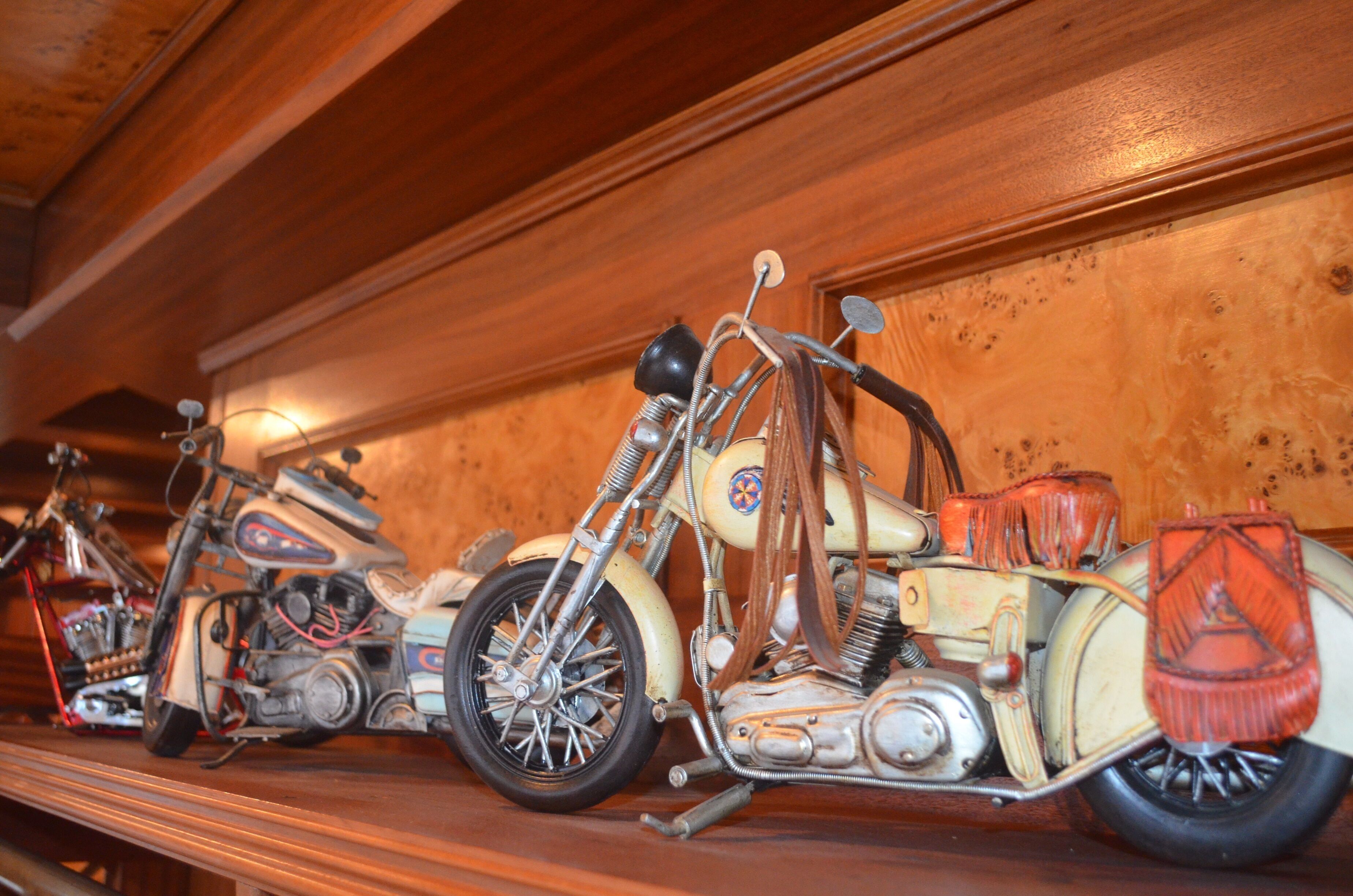 A wooden wall with a shelf displaying vintage motorcycles.