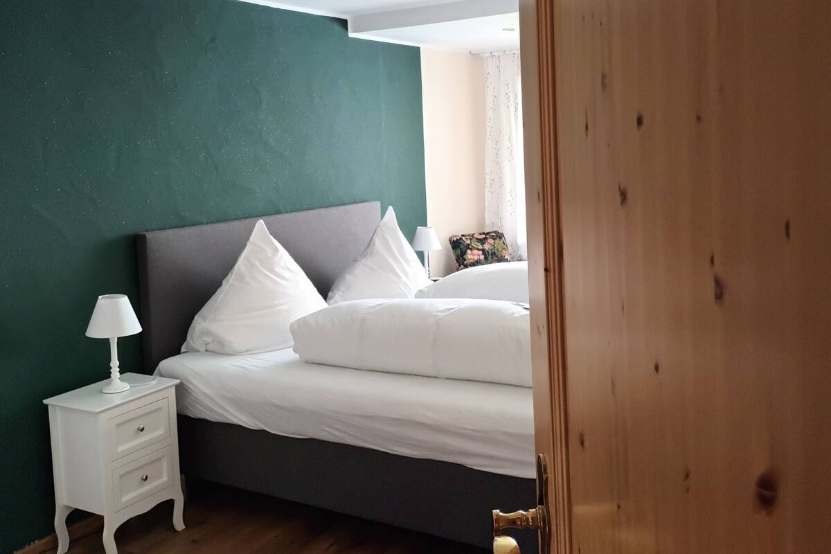 A bedroom with a bed, nightstand, and wooden wardrobe.