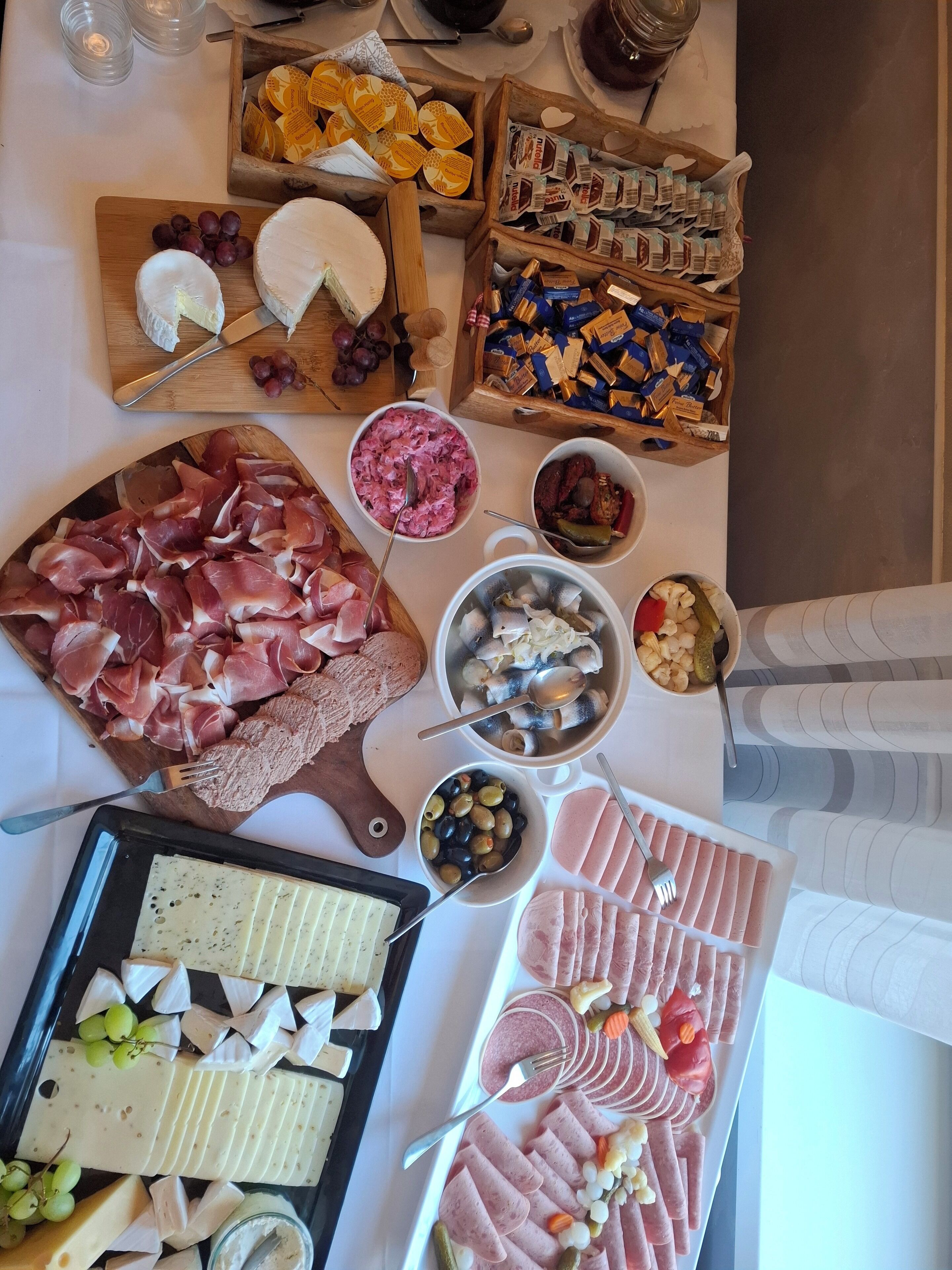 Een selectie kazen, gerookt vlees, olijven en ingelegde groenten, uitgestald op een tafel.