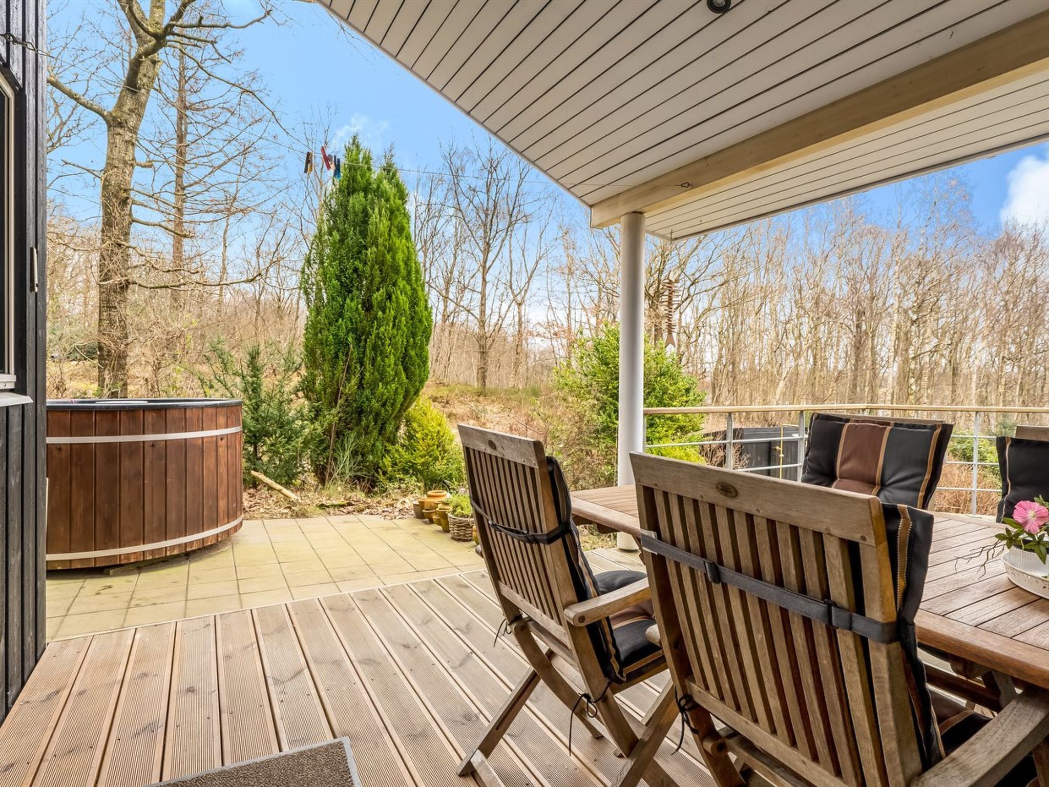 A covered outdoor patio with wooden furniture and a hot tub.