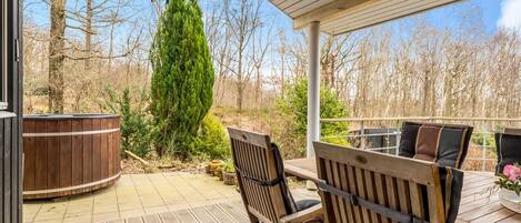 A covered outdoor patio with wooden furniture and a hot tub.