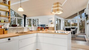 Een moderne keuken met witte kastjes, een groot kookeiland en hangende lampen.
