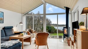 Een ruime woonkamer met een groot raam, een open haard en uitzicht op de omgeving.