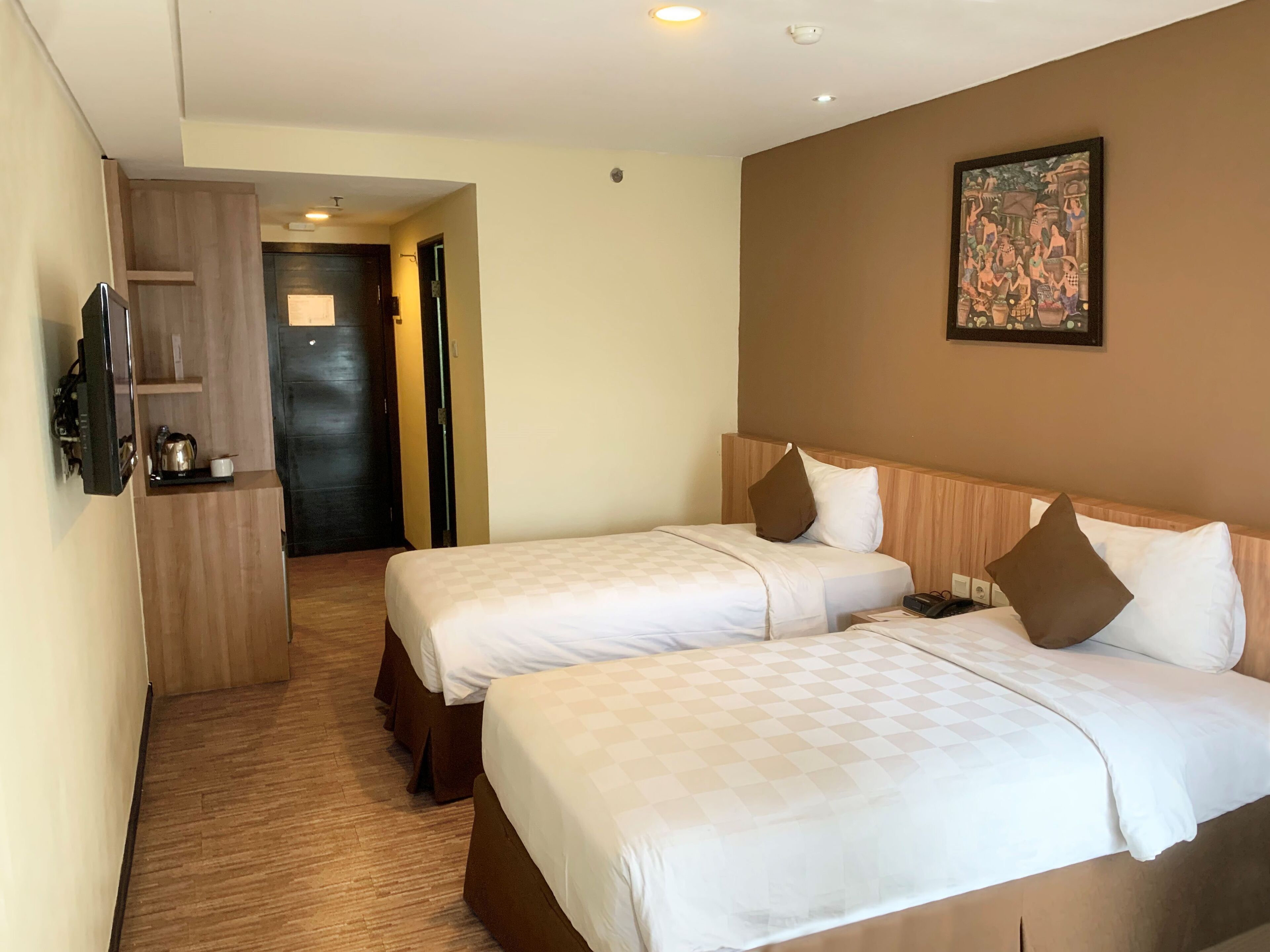 Una habitación de hotel con dos camas, televisión, un cuadro y un armario de madera.