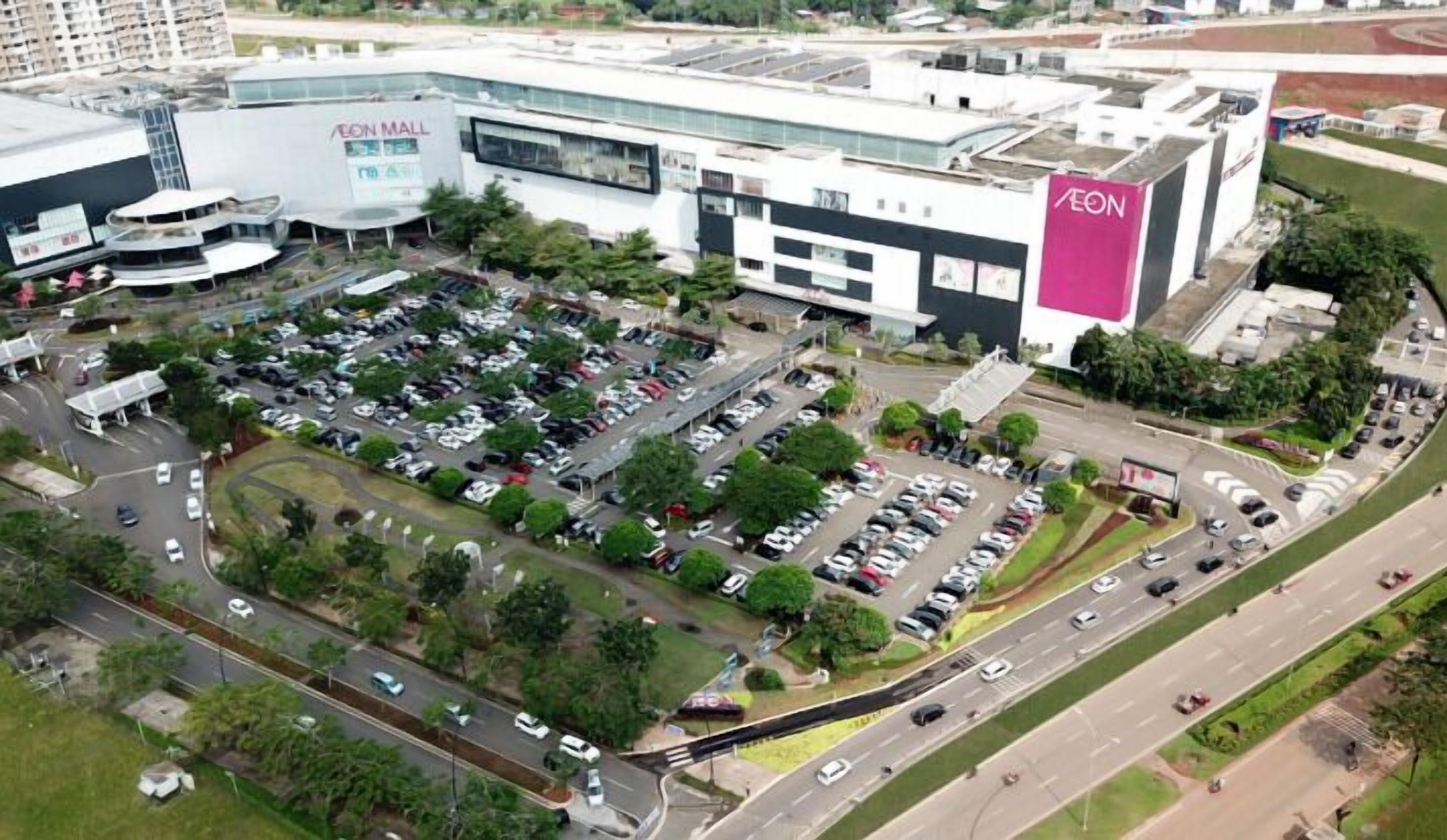 Un grande centro commerciale con parcheggio, diversi piani e un negozio AEON ben visibile.