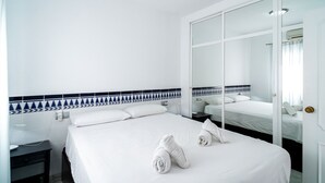 Una habitación de hotel con una cama grande, una mesita de noche, un espejo y un armario.