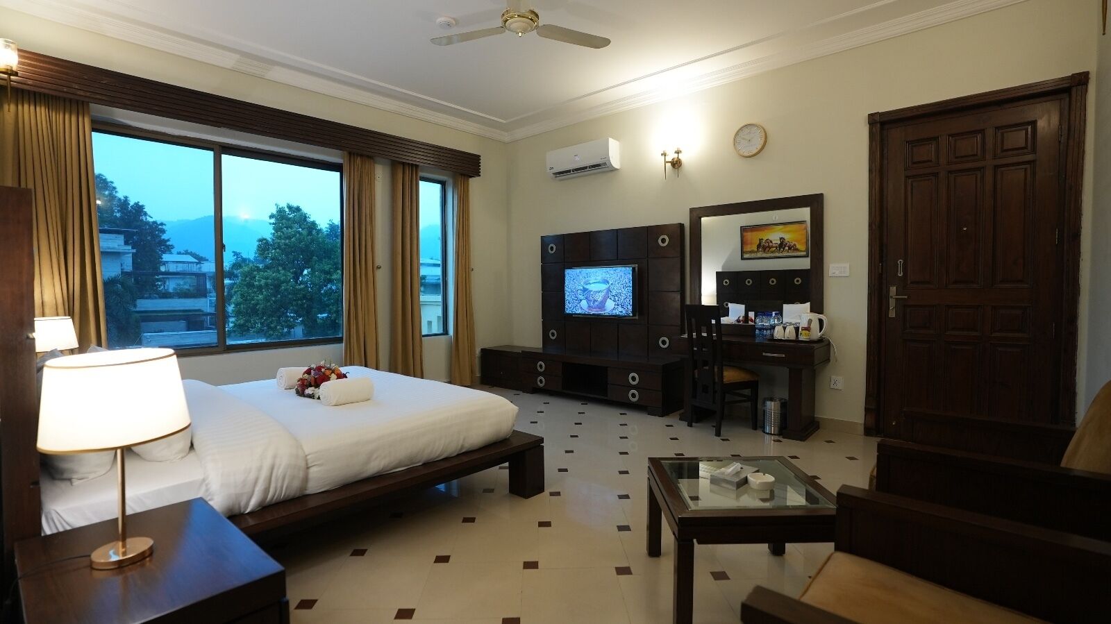Habitación de hotel con cama, escritorio, televisión, cafetera y vistas a las montañas.