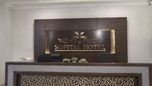 Un comptoir d’accueil avec une enseigne indiquant « HÔTEL SOFITAL » et un panneau décoratif en dessous.