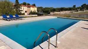 A rectangular swimming pool with a clear blue water surface, surrounded by a tiled deck. There are metal pool ladders on the right side, and a row of blue lounge chairs on the left. - VILLA BORA-BORA (Kassandra)
