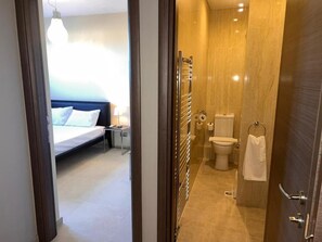 A hotel room with a bed, bedside table, lamp, and a view of the bathroom. - VILLA BORA-BORA (Kassandra)