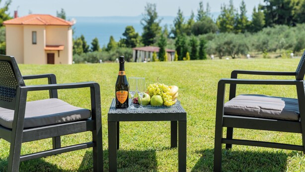 Two outdoor chairs with a table between them, holding a bottle, glasses, and fruit. - VILLA BORA-BORA (Kassandra)