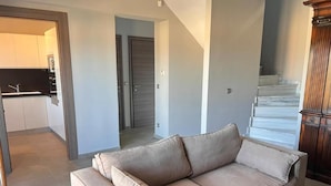 A living room with a beige sofa, a wooden cabinet, and a staircase. - VILLA BORA-BORA (Kassandra)