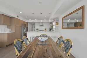 Eine moderne Küche mit weißen Schränken, einem Holztisch und vier Stühlen.
