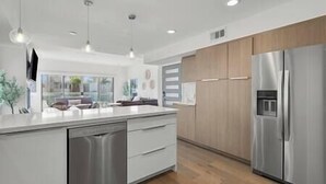 Una cocina moderna con un refrigerador de acero inoxidable, armarios blancos y un lavavajillas.