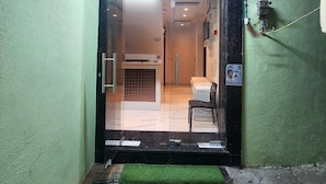 A hotel entrance with a reception desk, a sign indicating available rooms, and a green wall. - Cottage Yes Sir Dx (New Delhi)