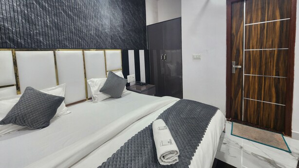 A modern hotel room with a large bed, a wardrobe, and a wooden door. - Cottage Yes Sir Dx (New Delhi)