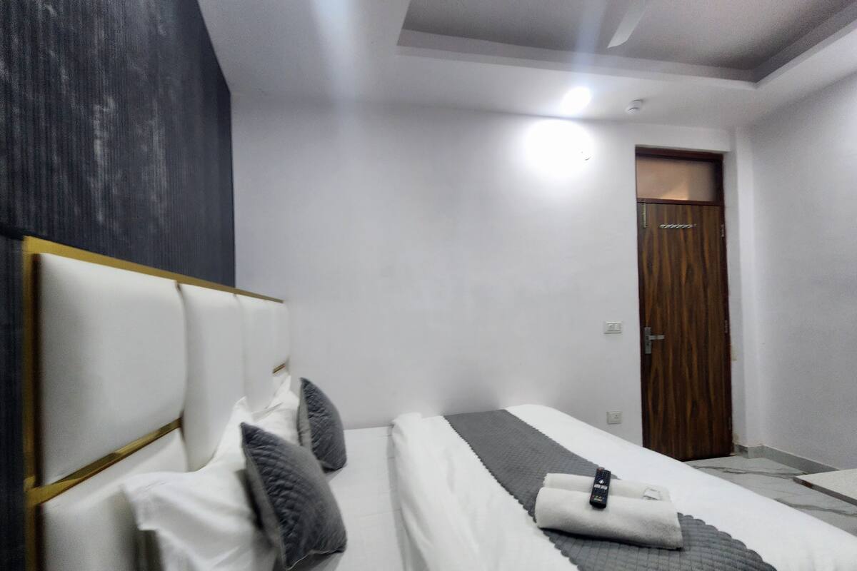 A modern hotel room with a large bed, a wooden door, and a white headboard.