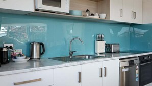 A modern kitchen with a sink, a kettle, a toaster, and a dishwasher.