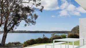 A deck with a table and benches overlooking a lake and distant hills.