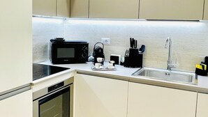 Een moderne keuken met witte kasten, een magnetron, een koffiezetapparaat en een spoelbak.