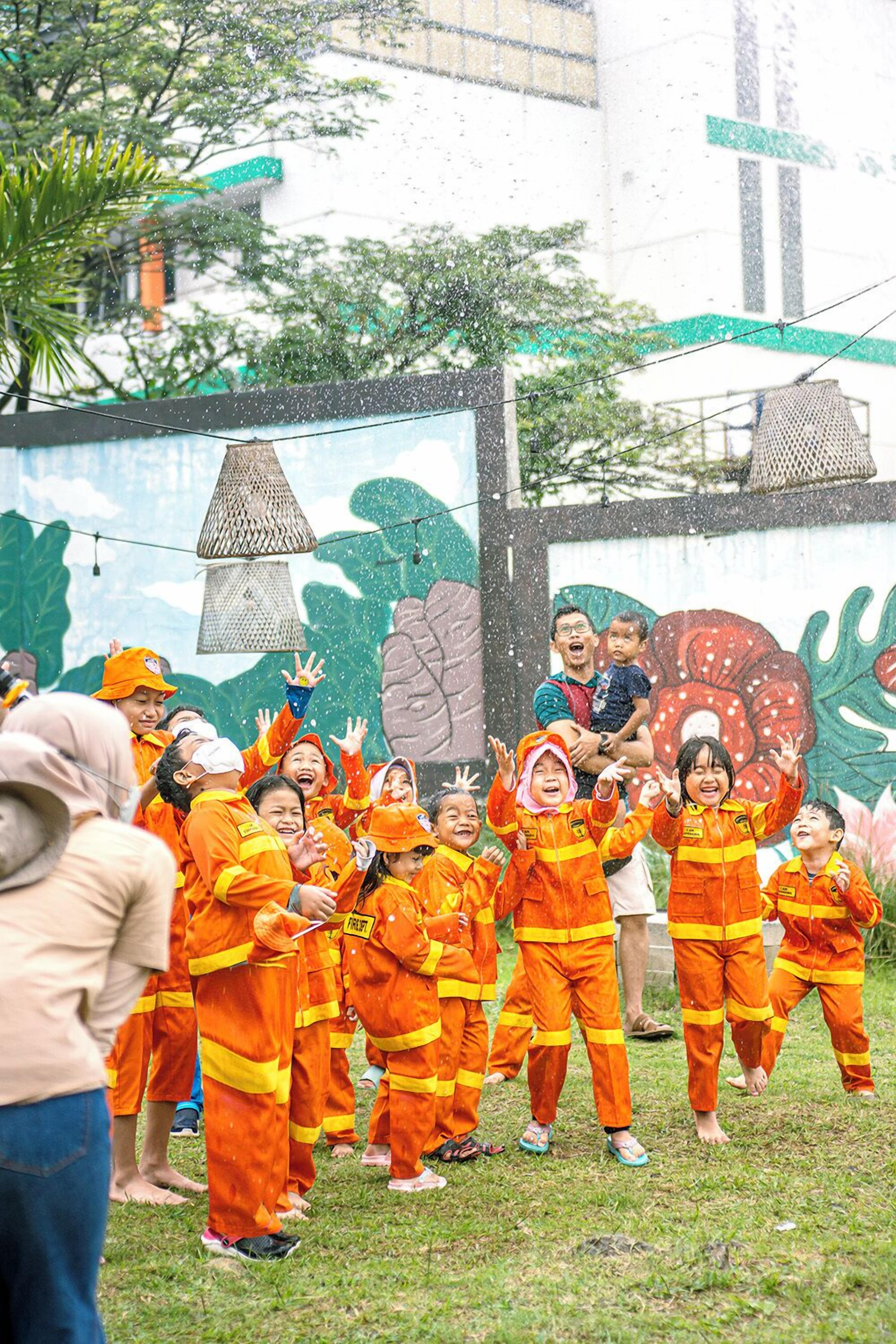 A group of people in orange uniforms standing on grass with a mural in the background.