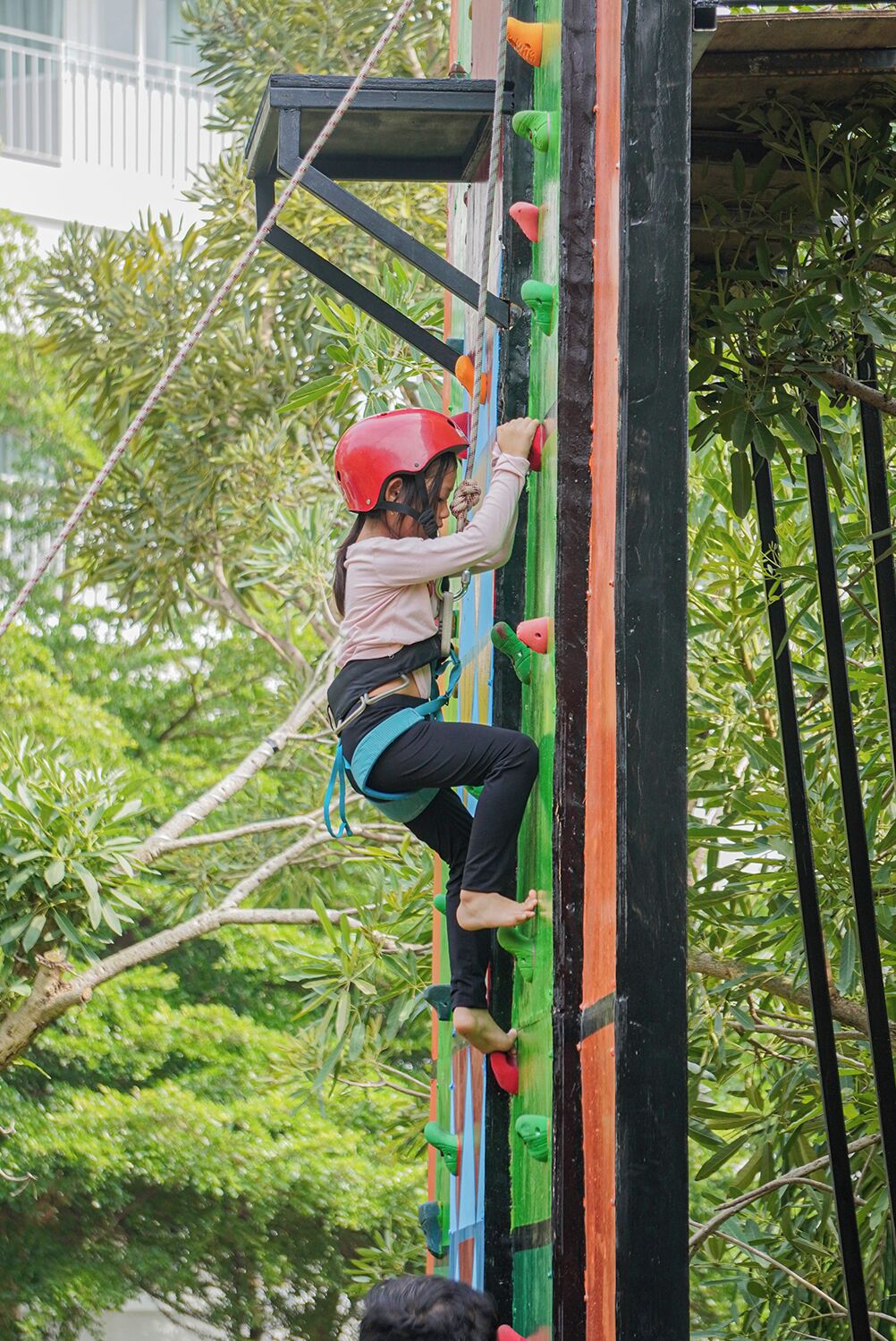 A person climbing a colorful climbing wall with various handholds and footholds.