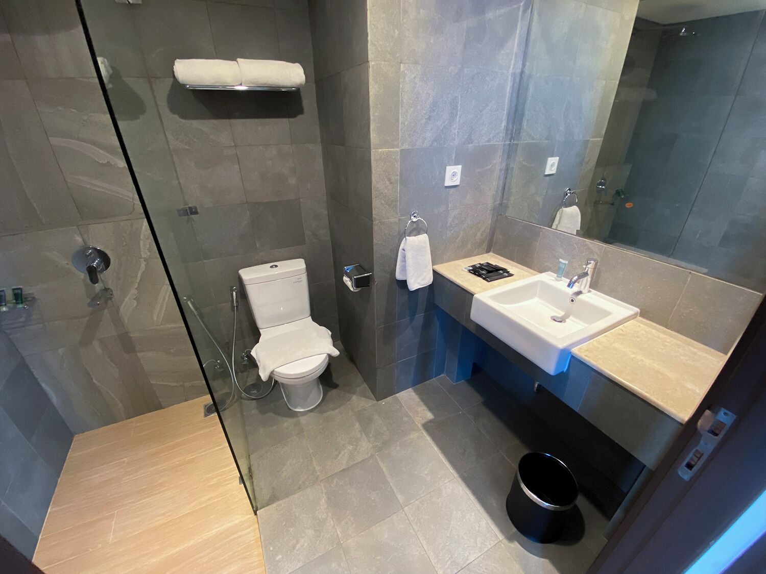 Un bagno moderno con doccia vetrata, un water, un lavandino e uno specchio.