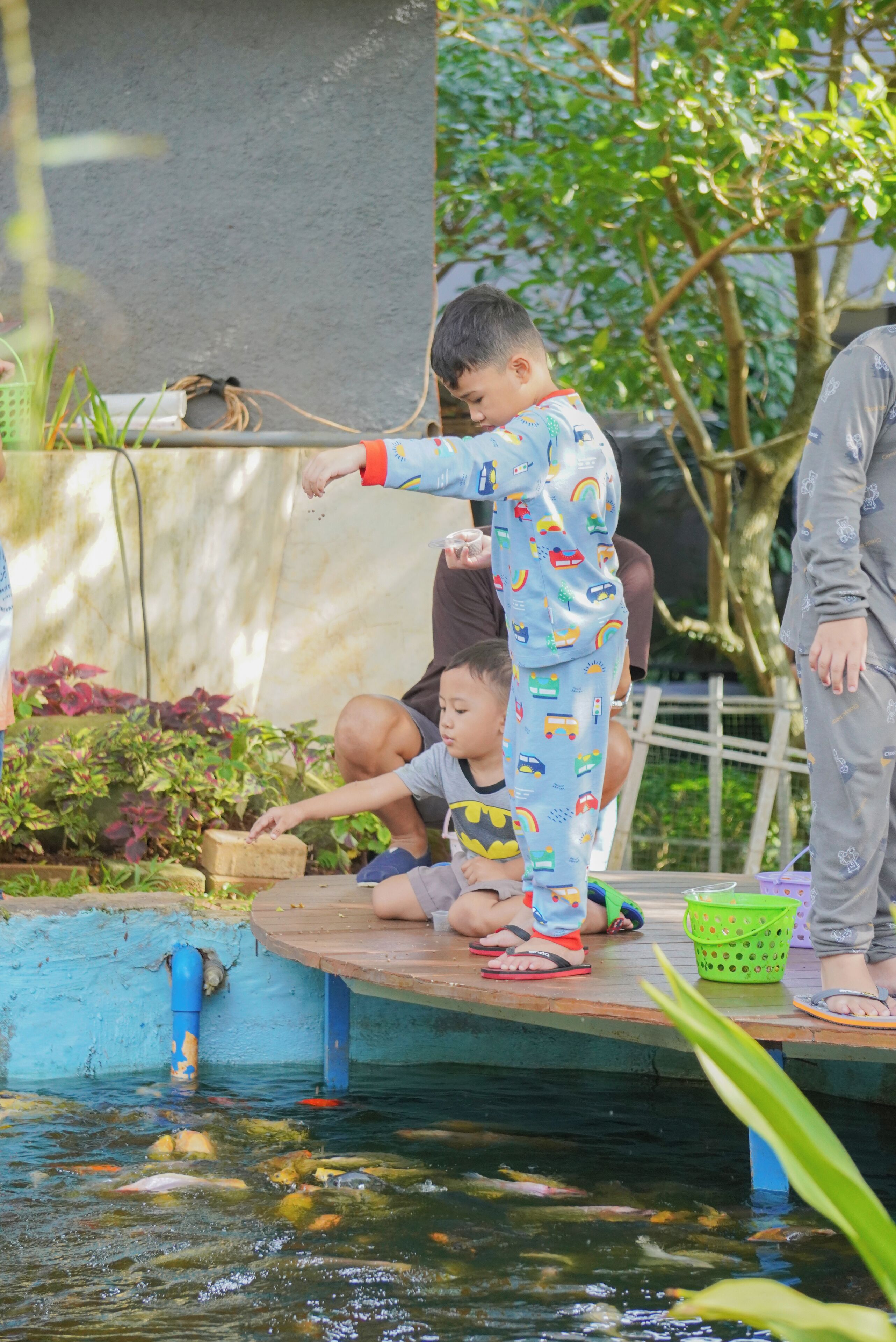 Niños jugando junto a un estanque con una plataforma de madera.