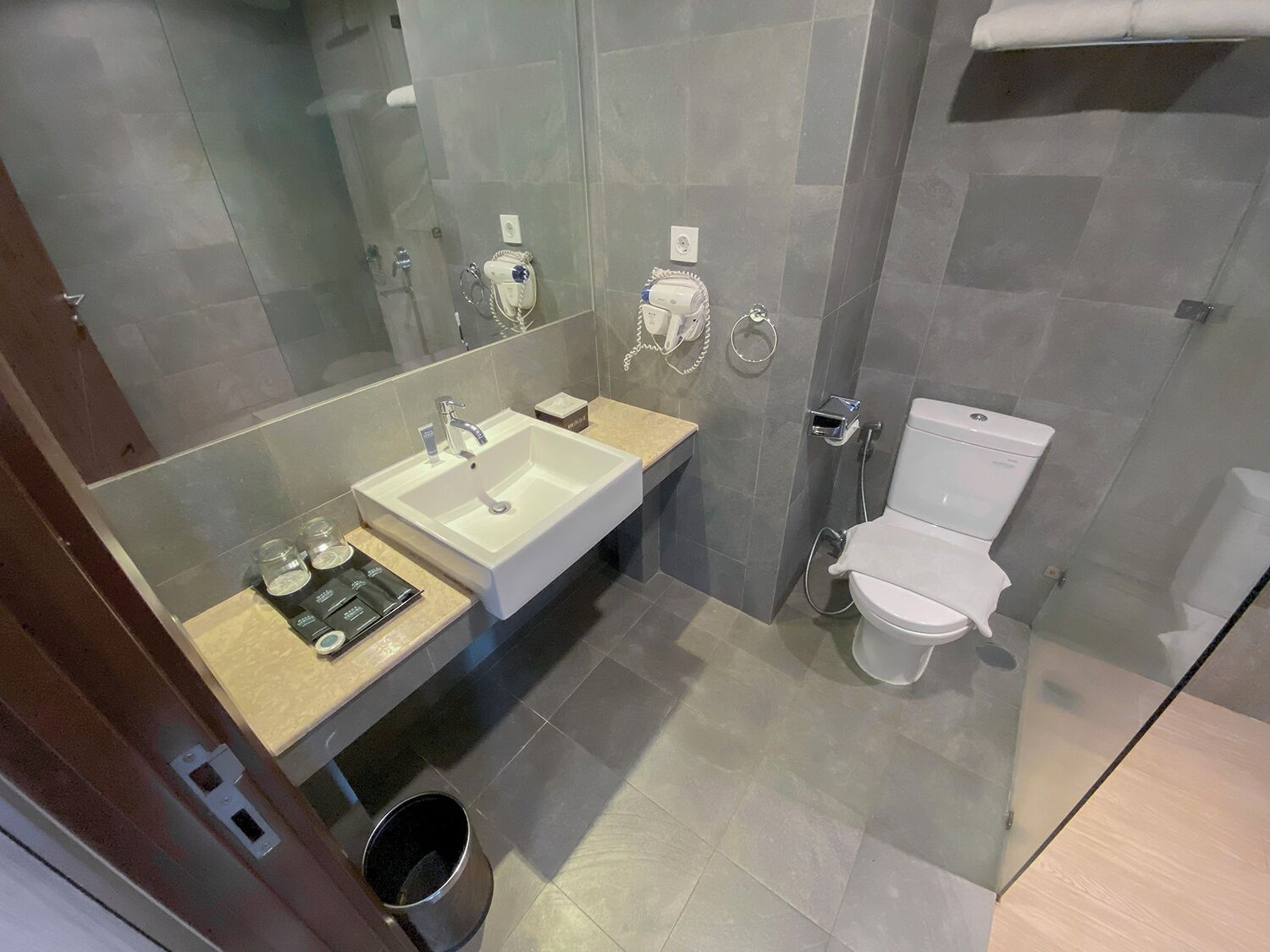 A modern bathroom with a large sink, toilet, and a mirror.