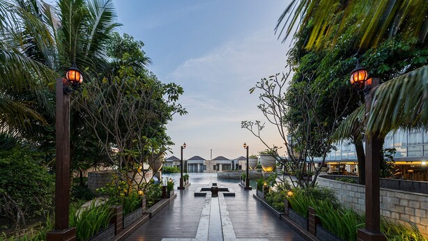 A pathway leading to a building with a water feature in the center, surrounded by greenery and illuminated by street lamps. - Nemuru Grand Bhuvana Ciawi (Ciawi)