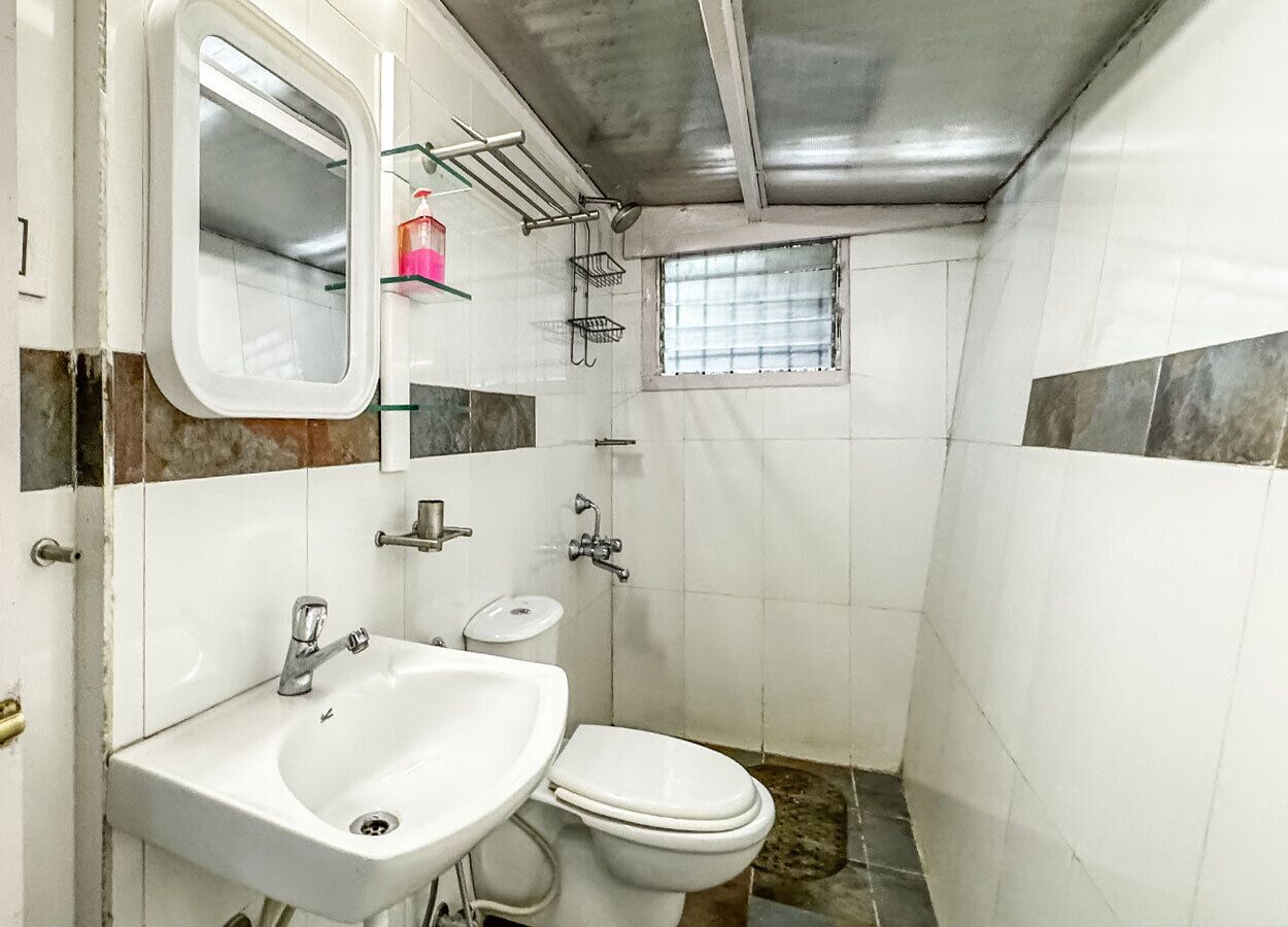 A compact bathroom with a sink, mirror, and toilet.