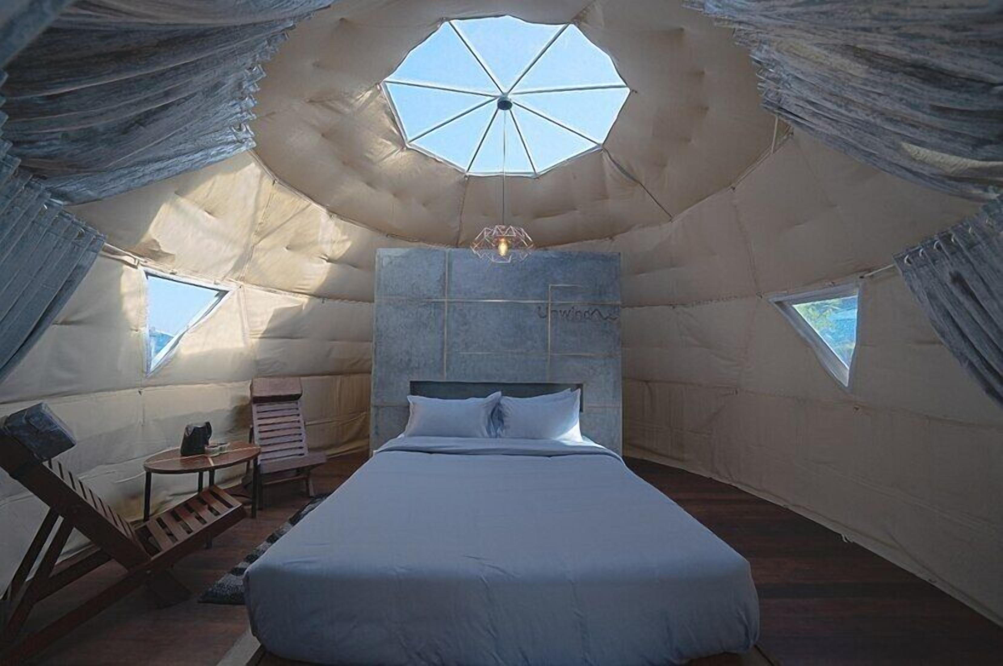 Un ambiente accogliente, simile a una tenda, con un letto, un tavolino e una sedia.