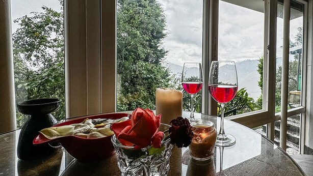 A table with a candle, a glass of red wine, a glass of white wine, and a bowl of food. - Manas Valley View bungalow  (Kodaikanal)
