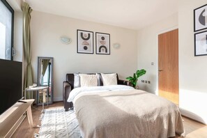 A modern bedroom with a large bed, a TV, a small table, and a mirror. - Cozy 1BR Near Tower Bridge - St Paul's Cathedral (London)