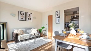 Un salon moderne avec un canapé, une table basse et un coin repas avec une table mise pour deux personnes.