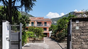 Una entrada con reja a un edificio, con pared de piedra y portón metálico.