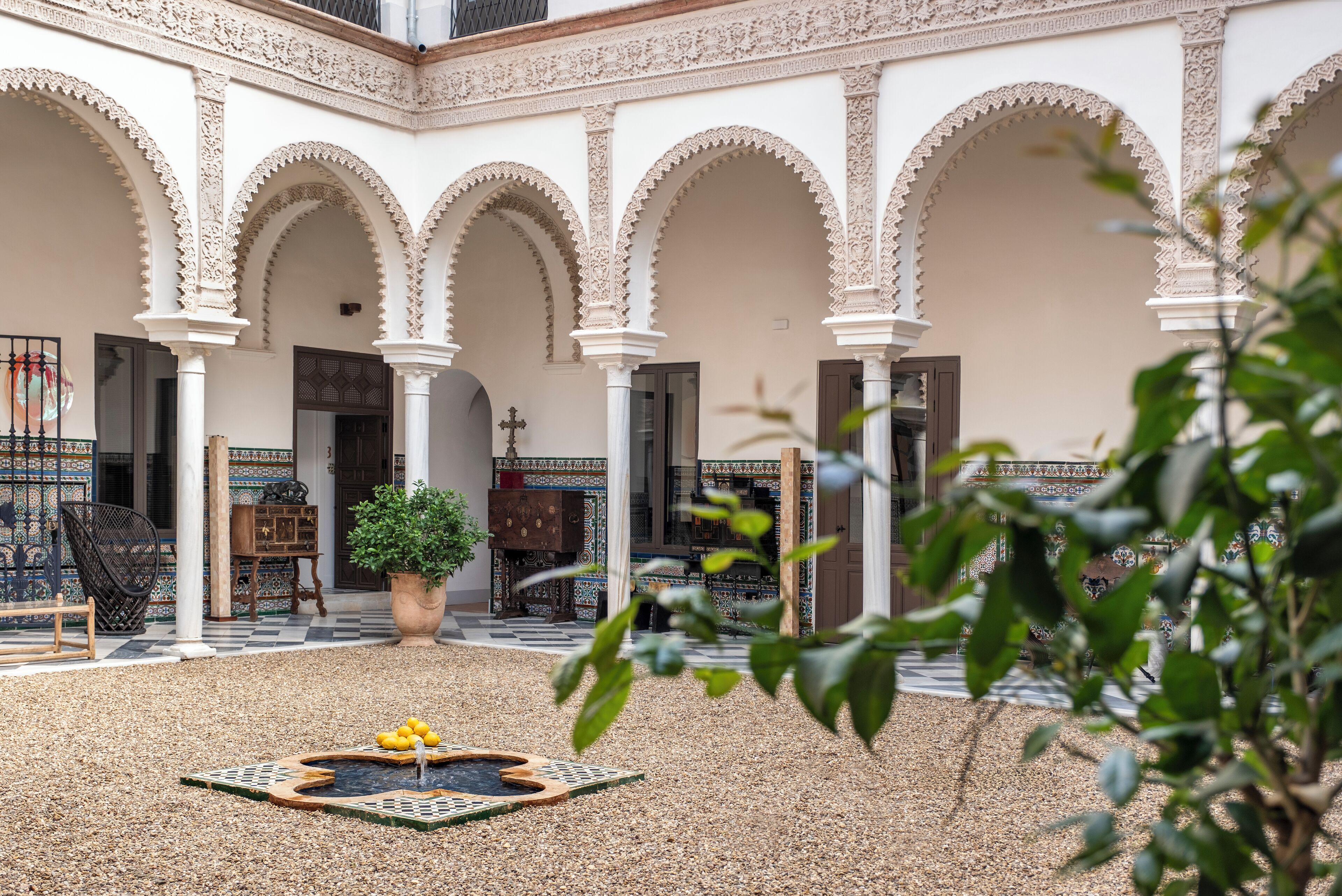 Un patio con arcos, una fuente y una planta en maceta.