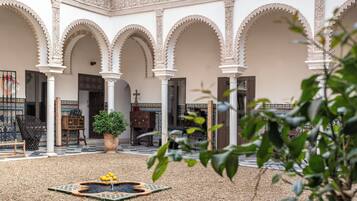Un patio con arcos, una fuente y una planta en maceta.