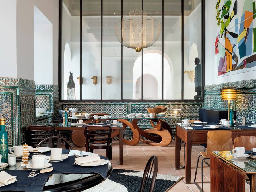 Un comedor con un ventanal grande, una araña y una pared con azulejos.