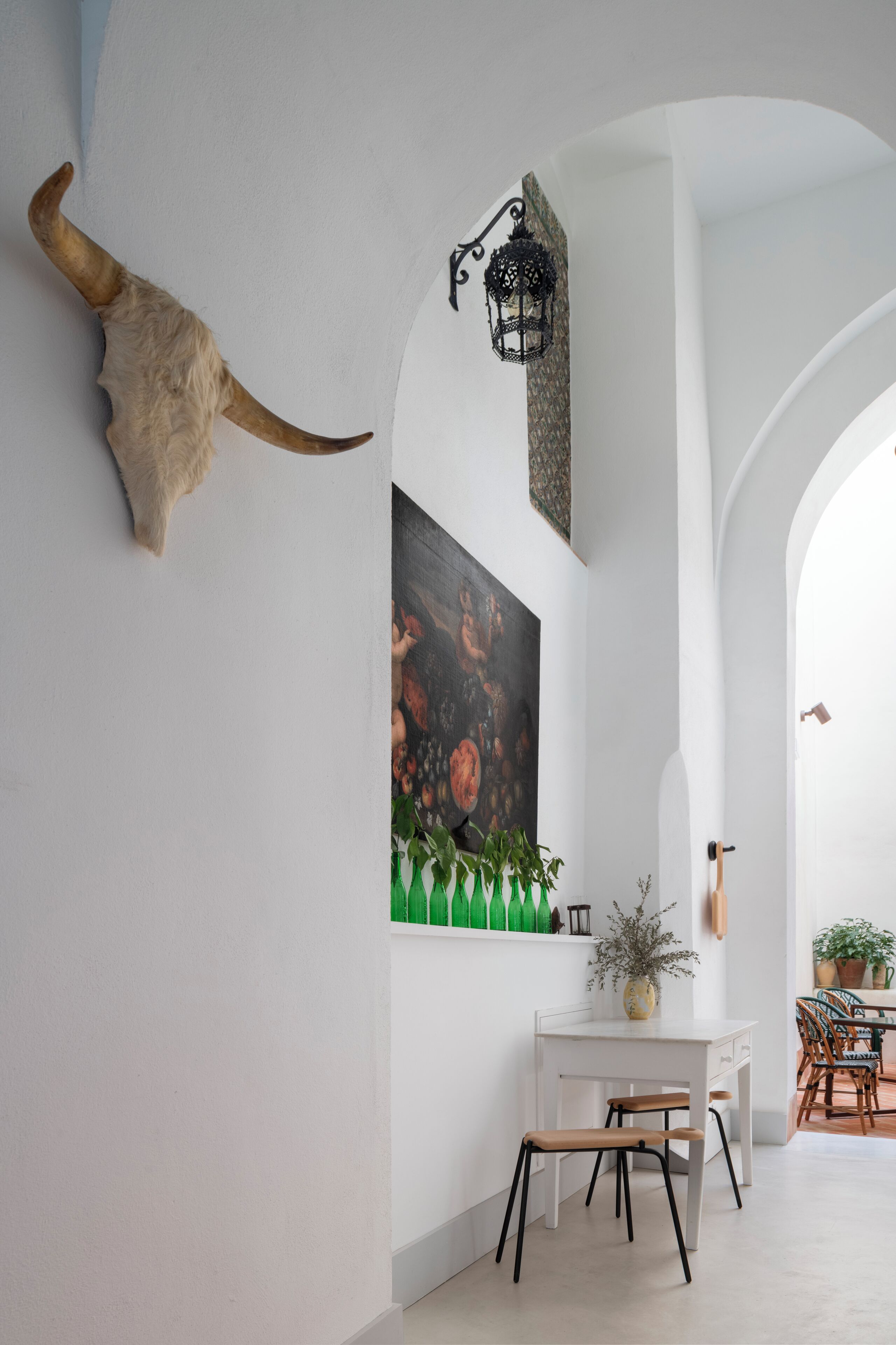 A dining area with a white table, chairs, and a large horn decoration on the wall.