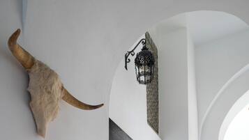 A dining area with a white table, chairs, and a large horn decoration on the wall.