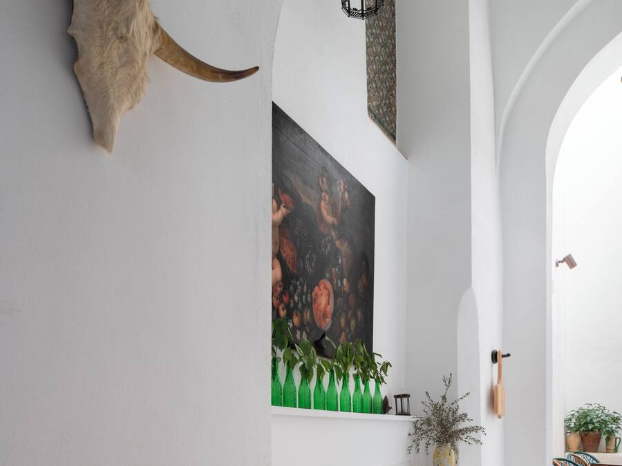 A dining area with a white table, chairs, and a large horn decoration on the wall.