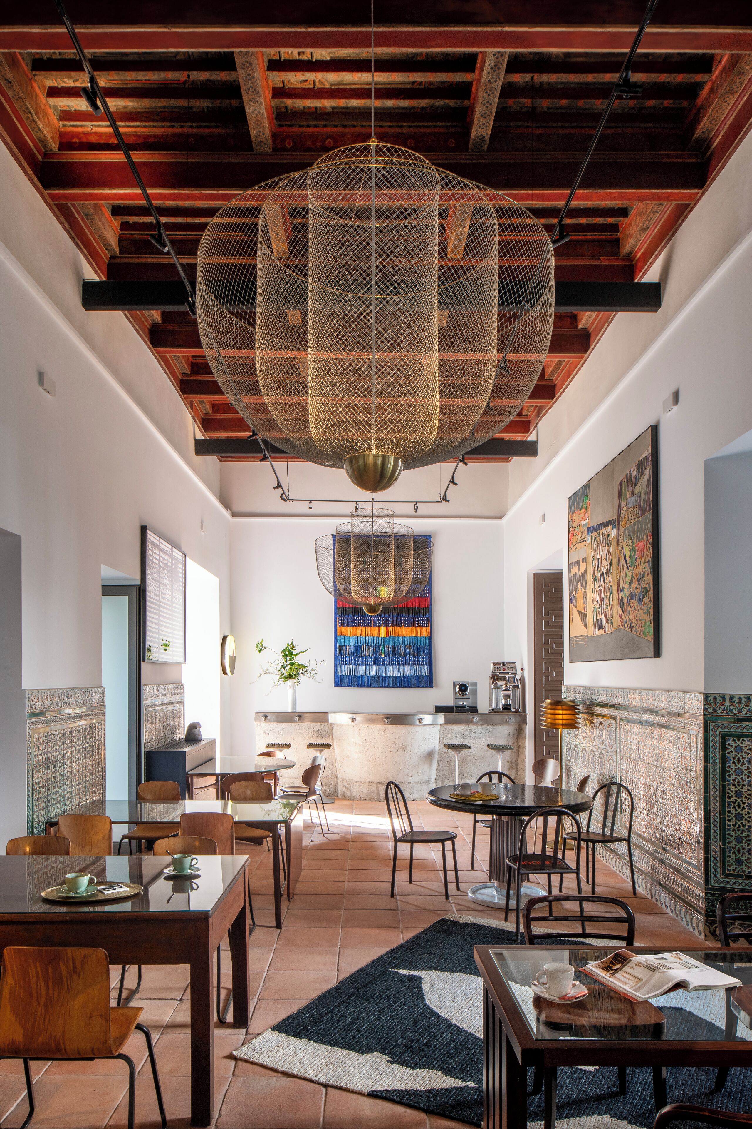 A spacious dining area with high ceilings, exposed beams, and a large hanging light fixture.