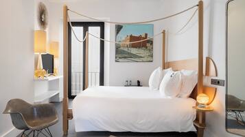 Un dormitori modern amb un llit amb cortines, una cadira bressol, una tauleta de nit amb làmpades i un quadre a la paret.