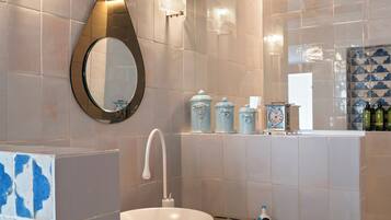A modern bathroom with a large white sink, a mirror, and a towel rack.