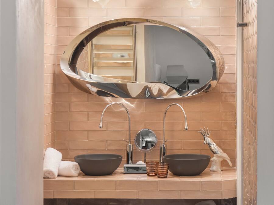 Un baño con lavamanos doble, un espejo grande y un perchero para toallas.