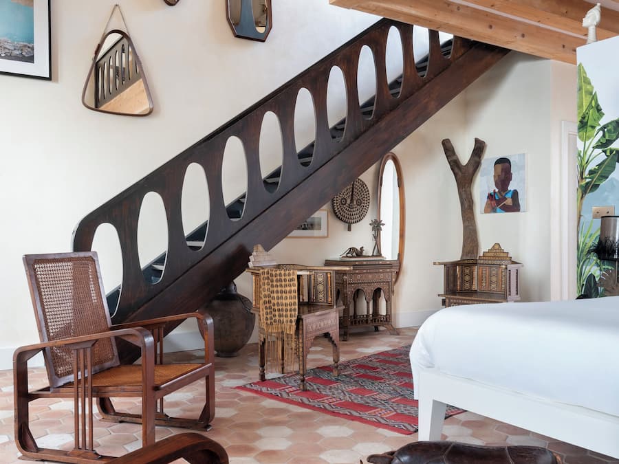 Un dormitorio con escaleras de madera, una cama, una mesa de comedor y una silla.